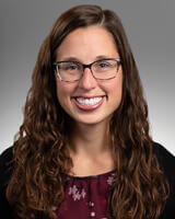 Alyssa Robley wearing  black and dark red with glasses and long dark hair