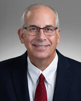 Morris Hund in black and white suit with red tie and glasses